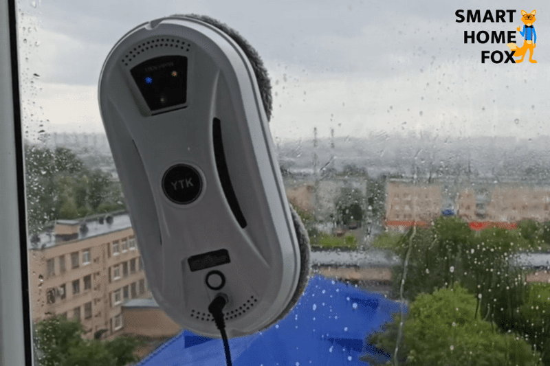 Man sieht einen runden Fensterreinigungsroboter auf der Glasscheibe.